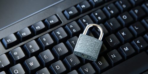 A high angle shot of a lock on a black computer keyboard on a black surface